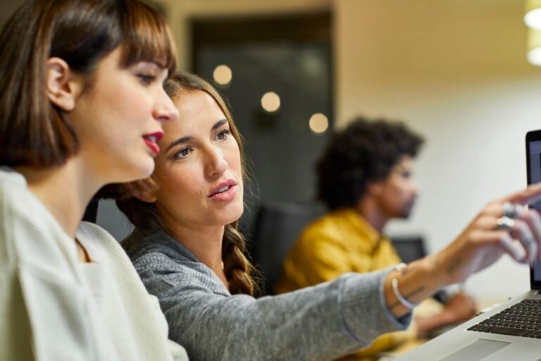 duas mulheres conversando olhando para o computador
